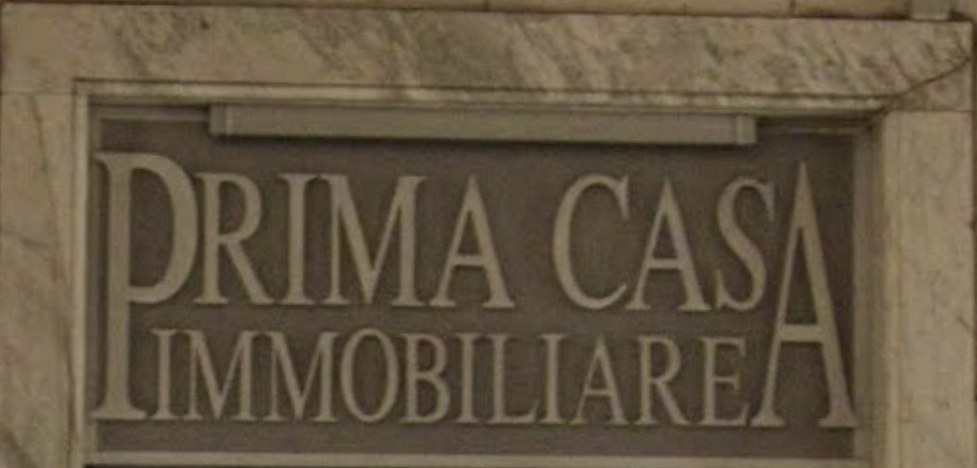 L'insegna in pietra di Prima Casa Immobiliare in Via Paleocapa